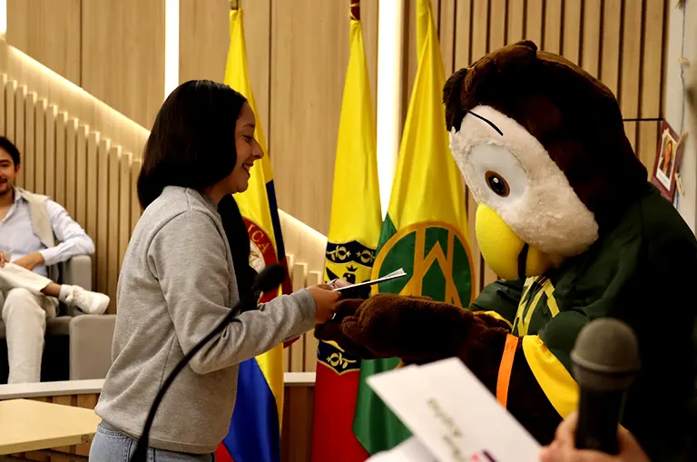 Estudiante recibe diploma de finalización del Verano DELFÍN 2026 durante la ceremonia de clausura en la Universidad de América.